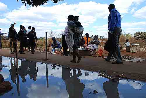 BUSINESS AS USUAL: Residents of Kuwadzana 3 Township in Harare, Zimbabwe, Novermber 2007, Walk past raw sewage. Vegetable vendors also go on with selling their tomatoes despite the stench from the raw sewage. © IRIN